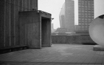 B&W esit on the roof of a building with sky scrapers in the foreground and security cameras for every angle